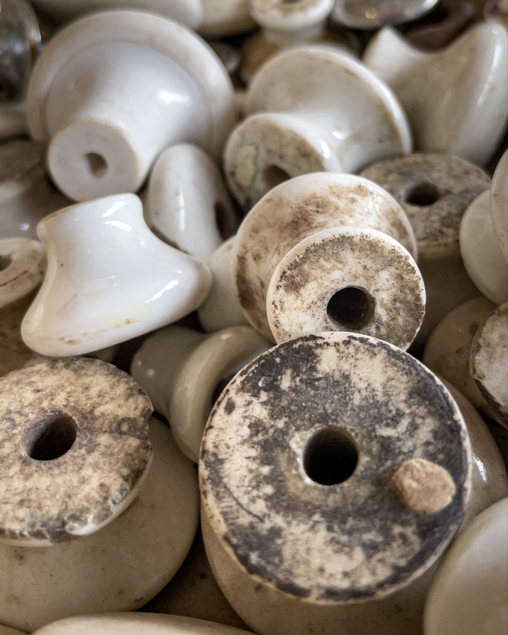 A close-up of old, white ceramic drawer knobs, with some showing signs of dirt and wear.