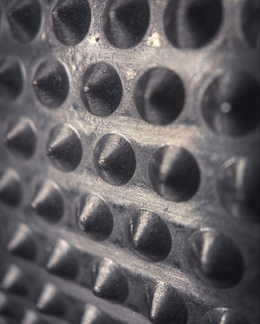 Macro photo of a metal object with a grid of dull spikes.