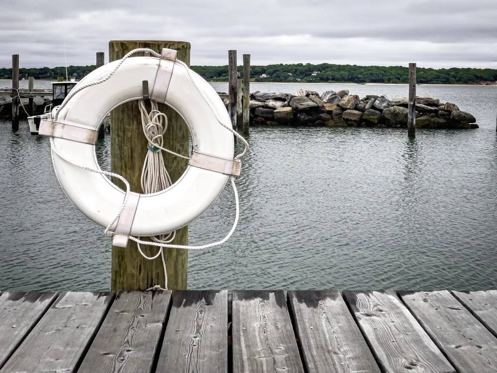 Photo of a life preserver mounted along a dock in front of a harbor on a stormy day